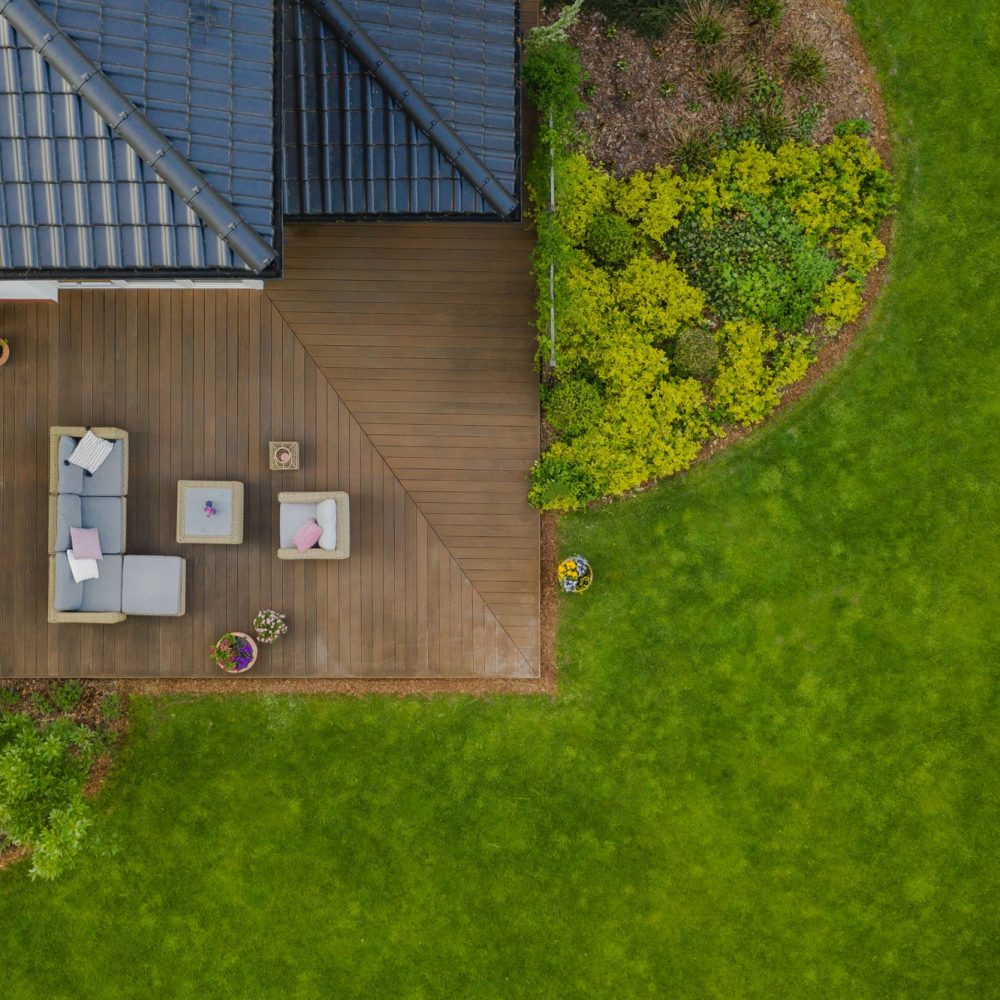 Top view of suburban house with green garden and wooden terrace